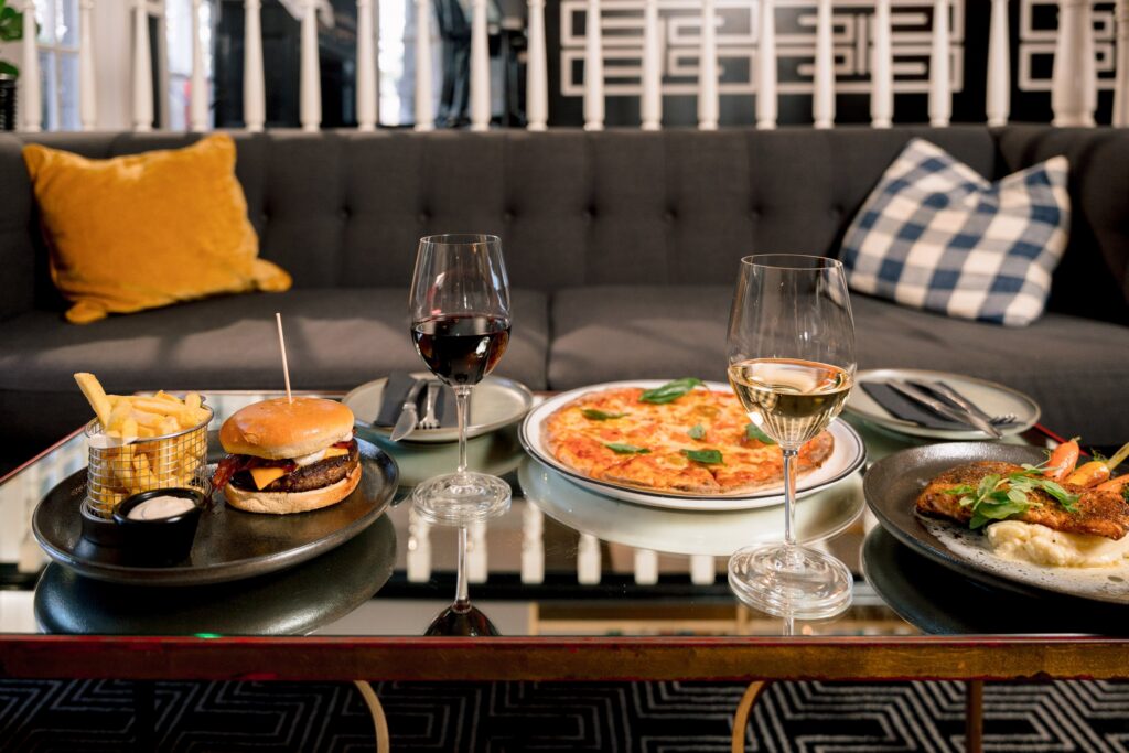 Wood-fired pizza, a burger and drinks on the glass table at Epoche Lounge Bar