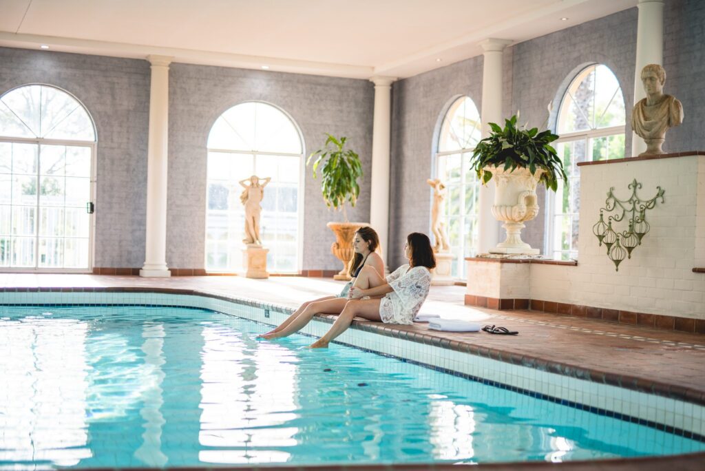 Guests relaxing by the heated indoor pool at voco Kirkton Park
